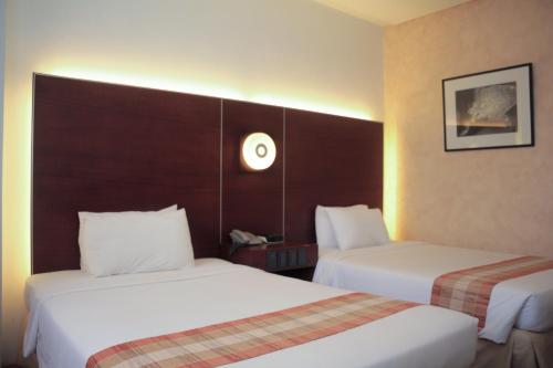 two beds in a hotel room with white sheets at Casablanca Suites Near Airport in Legazpi
