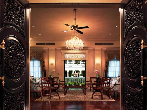 a dining room with a table and chairs and a chandelier at Hotel Majapahit Surabaya MGallery in Surabaya