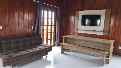 sala de estar con sofá y TV en Recanto Aurora, en Massiambu Pequeno