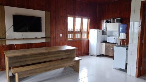 cocina con pared de madera y TV de pantalla plana en Recanto Aurora, en Massiambu Pequeno