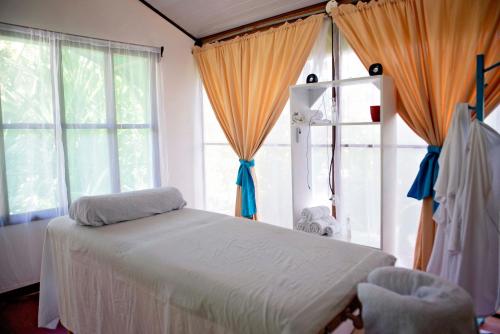 a bedroom with a bed and two large windows at Hotel Tortuguero Beachfront in Tortuguero