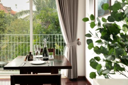 a table with wine bottles and glasses in front of a window at Pegasy Premium Suites & Residence Westlake in Hanoi