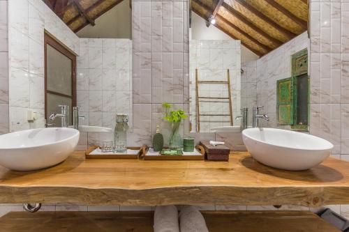 two sinks on a wooden table in a bathroom at Rumi Villas in Seminyak