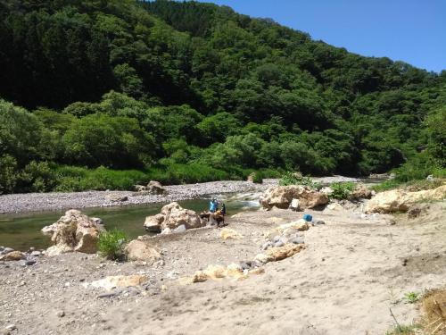 a group of people standing on a beach next to a river at Akiu Canada 鴻の巣温泉 Konosu Onsen in Sendai