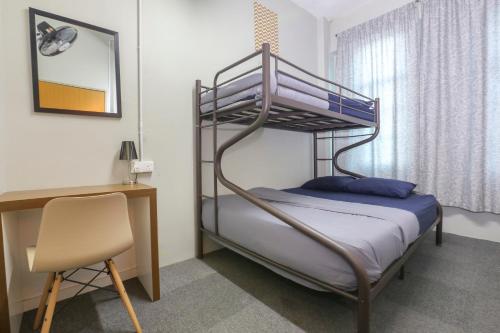 a bedroom with a bunk bed with a desk and a chair at SPOT ON 89751 Bed Station Guest House in Tanah Rata