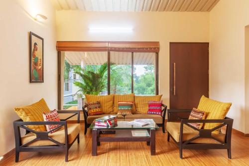 a living room with a couch and a table and chairs at StayVista's Green Grove - A Modern Mountain-View Retreat with Lush Lawn in Trimbak