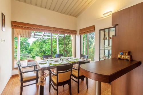 a dining room with a wooden table and chairs at StayVista's Green Grove - A Modern Mountain-View Retreat with Lush Lawn in Trimbak