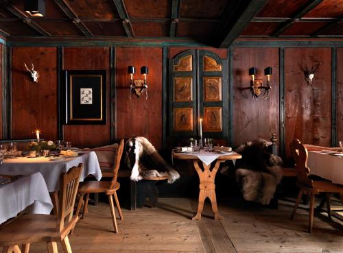 a dining room with two tables and a person standing in front of it at House of Hütter - Wachtelhof Hotel & Spa in Maria Alm am Steinernen Meer