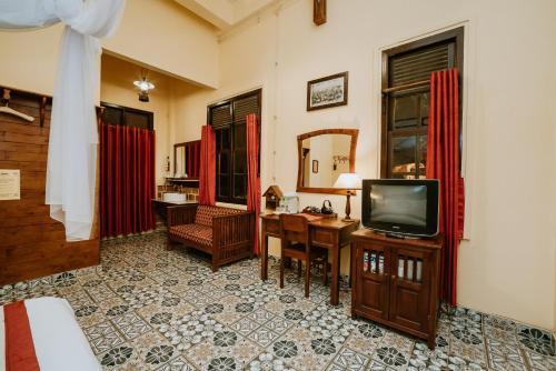 大叻的住宿－沙非大叻酒店，客厅配有电视、书桌和书桌。