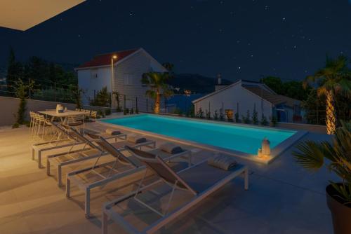 a swimming pool at night with lounge chairs around it at Villa Juliet in Trogir