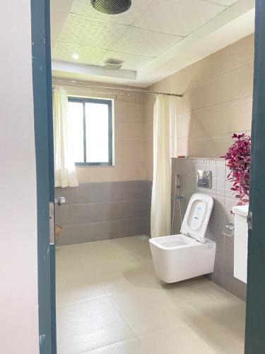 a bathroom with a toilet and a window at Mannoor Farms Mountain View Stays, Munnar in Munnar