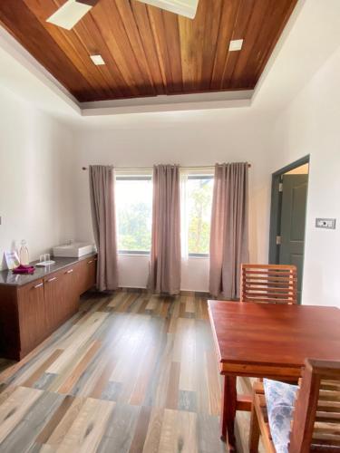 a living room with a wooden table and windows at Mannoor Farms Mountain View Stays, Munnar in Munnar