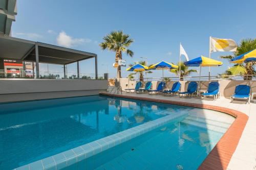 a swimming pool with blue chairs and umbrellas at Marilyn Apartments in Rethymno Town