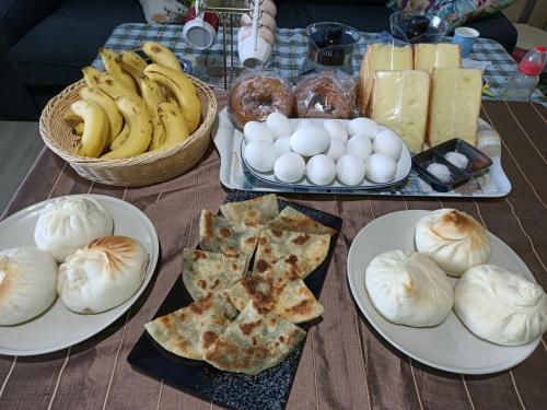 einen Tisch mit Teller mit Speisen, Brot und Eiern in der Unterkunft Sports Home in Xingjian