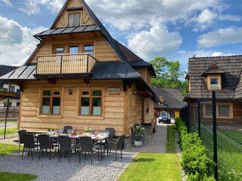 a wooden house with a table in front of it at Domki Vika Home i Wataha Home - świetna lokalizacja w centrum Zakopanego - 10min pieszo do Krupówek! in Zakopane