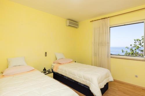 twee bedden in een kamer met een groot raam bij Apartment Milic in Dubrovnik