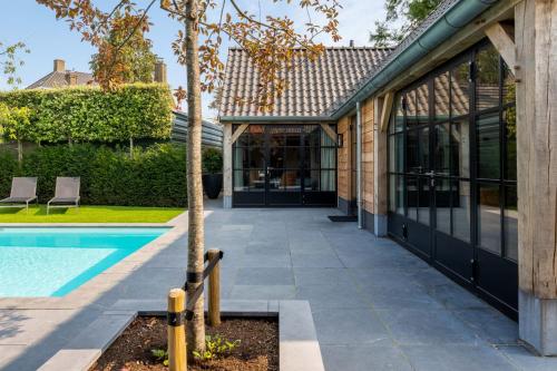 a house with a swimming pool and a tree at Sjiek Basiliek in Oudenbosch