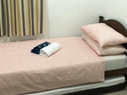 ein Bett mit einer rosa Decke und Handtüchern darauf in der Unterkunft Menara U Shah Alam Guest House in Shah Alam