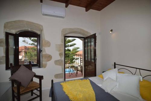 a bedroom with a bed and a chair and windows at Villa Christini a luxury villa with amazing views in Tzitzifés