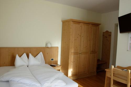 a bedroom with a bed with white pillows at Guesthouse - Cultural Center Gustav Mahler in Dobbiaco
