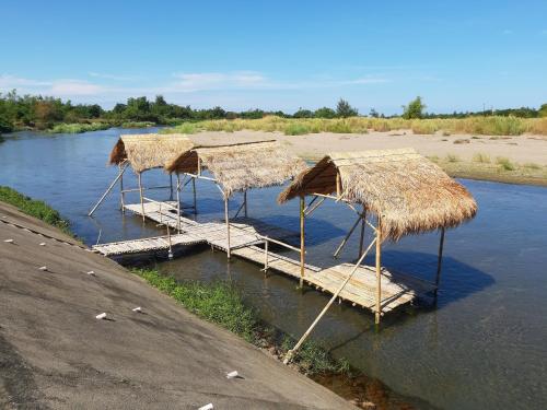 a group of straw umbrellas on a river at Monty's Riverside View Resort in San Antonio