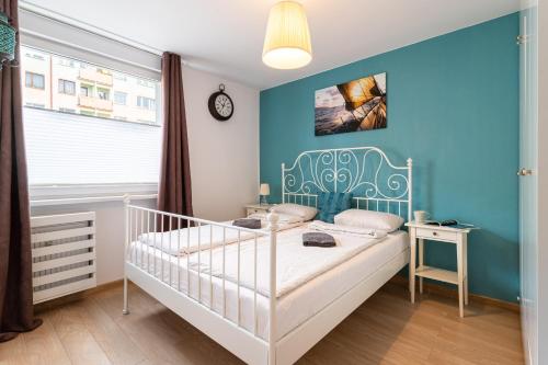 a bedroom with a white crib and a blue wall at Victus Apartamenty, Apartament Livia in Sopot