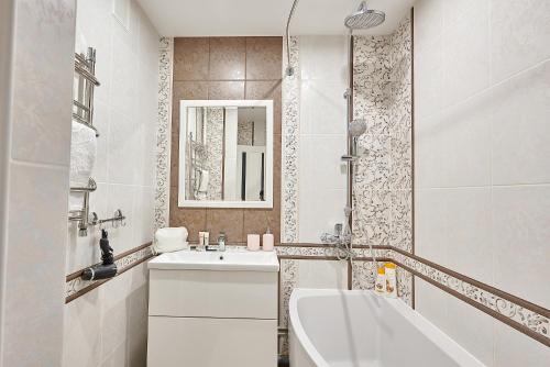 Baño blanco con bañera y lavamanos en PaulMarie Apartments on Yunosti, en Mazyr