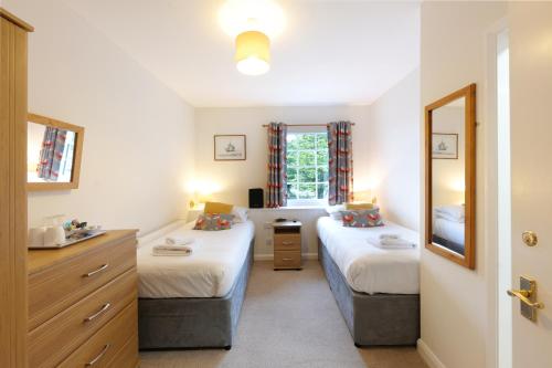 布德的住宿－布蘭登阿姆斯酒店，一间卧室设有两张床、一个水槽和镜子