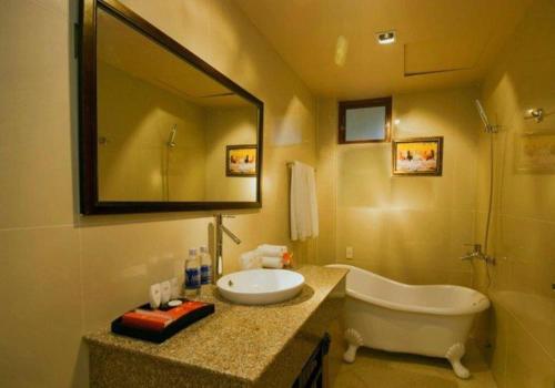 uma casa de banho com uma banheira, um lavatório e um espelho. em Song Tien Annex Hotel em Mỹ Tho