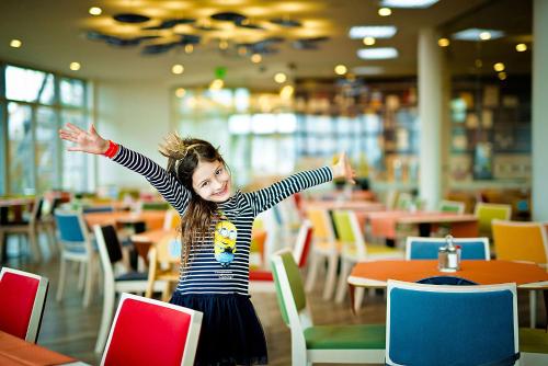 a little girl with her arms out in a restaurant at Kolping Holiday Resort in Hévíz