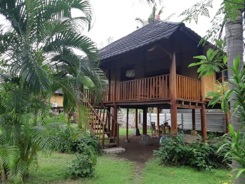 a wooden house with a deck in a forest at Tangga Bungalows in Gili Islands