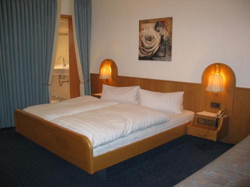 a bedroom with a large bed with two lamps at Hotel-Restaurant-Kolb in Illertissen