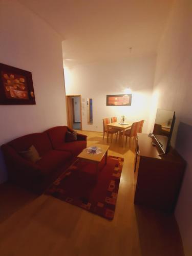 a living room with a red couch and a table at Altwernigeröder Apparthotel in Wernigerode