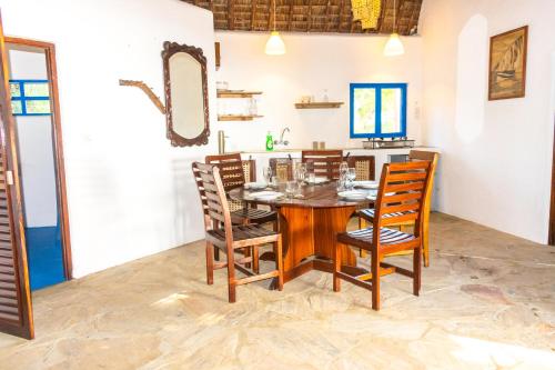 a dining room with a wooden table and chairs at Hibiscus Beach House in Pangani