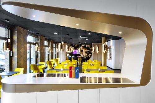 a restaurant with yellow chairs and a counter at Prize by Radisson, Erfurt City in Erfurt