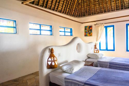 two beds in a room with blue and white at Hibiscus Beach House in Pangani