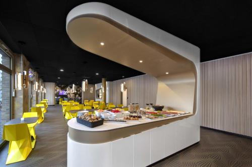 a restaurant with yellow chairs and a counter with food at Prize by Radisson, Erfurt City in Erfurt