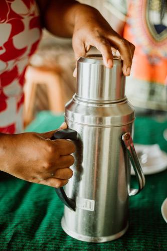 a person is holding the handle of a metal thermos at Hibiscus Beach House in Pangani