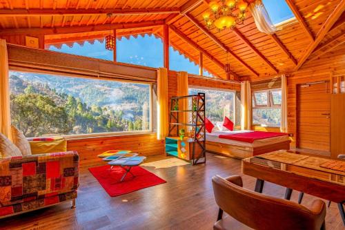 uma sala de estar com uma cama, uma mesa e janelas em Golden Bliss Cottage by VEO - Part of StayVista em Rāmgarh