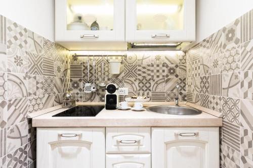 a white kitchen with a sink and tiles on the wall at Sweet Life Trevi Roma in Rome