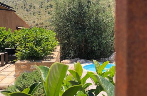 a swimming pool in a garden with trees and bushes at Baglio La Porta by Geocharme in San Vito lo Capo