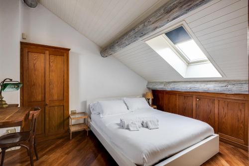 una camera con un letto, una finestra e una scrivania di Duplex incantevole sui tetti nel cuore dei Navigli a Milano