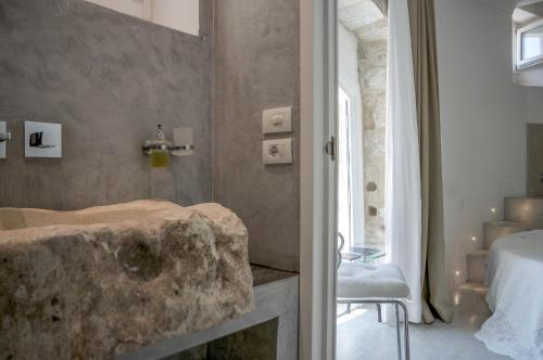モーディカにあるAnime a Sud - Residenza Hortusのバスルーム(石造りの洗面台、ベッド付)