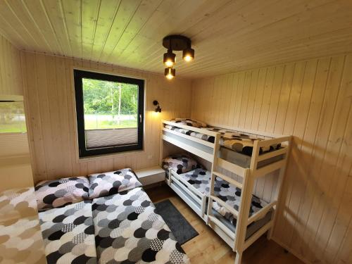 a bedroom with two bunk beds and a window at Amber Domki in Jarosławiec