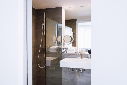 a bathroom with a sink and a shower with mirrors at Pillows City Hotel Brussels Centre in Brussels