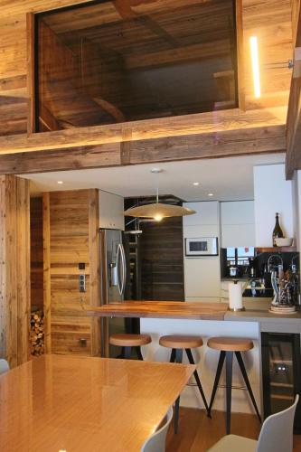 - une cuisine avec des murs en bois et une table avec des tabourets dans l'établissement MARMOTTE 203 - Magnifique duplex aux pieds des pistes, à Bonneval-sur-Arc