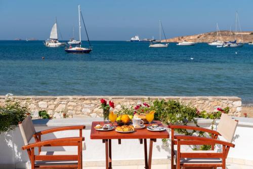 a table with fruit and vegetables on a balcony with the water at Irene Studios - Beachfront in Parikia