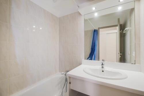 une salle de bain avec un lavabo, une baignoire et un miroir dans l'établissement Résidence le Hameau des Ecrins - maeva Home, à Puy-Saint-Vincent