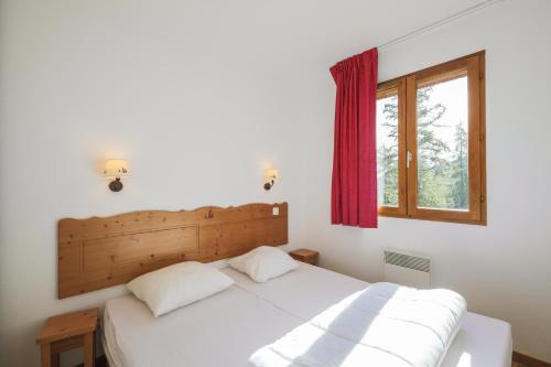une chambre avec un lit blanc et une fenêtre dans l'établissement Résidence le Hameau des Ecrins - maeva Home, à Puy-Saint-Vincent