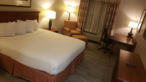 a hotel room with a large bed and a chair at Country Inn & Suites by Radisson, Manchester Airport, NH in Bedford